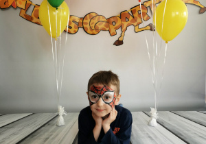 Chłopiec leży na tle fotograficznym i pozuje do zdjęcia wśród balonów.
